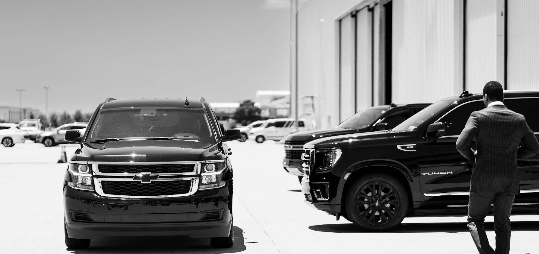 Executive walking towards a fleet of black SUVs